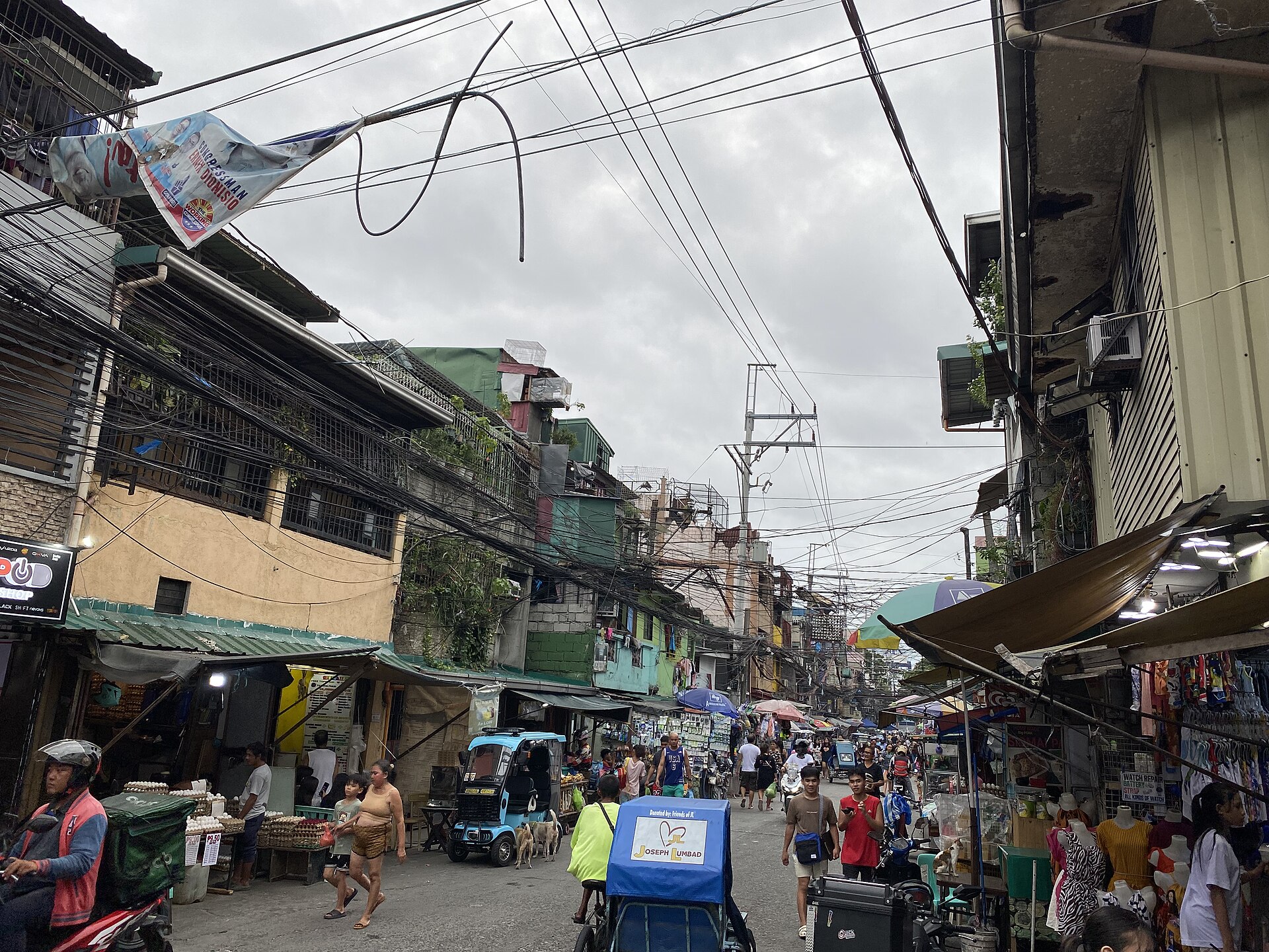 Pacheco Street in Tondo: shops, pedestrians, tricycles, and overhead utilities share a relatively narrow street.