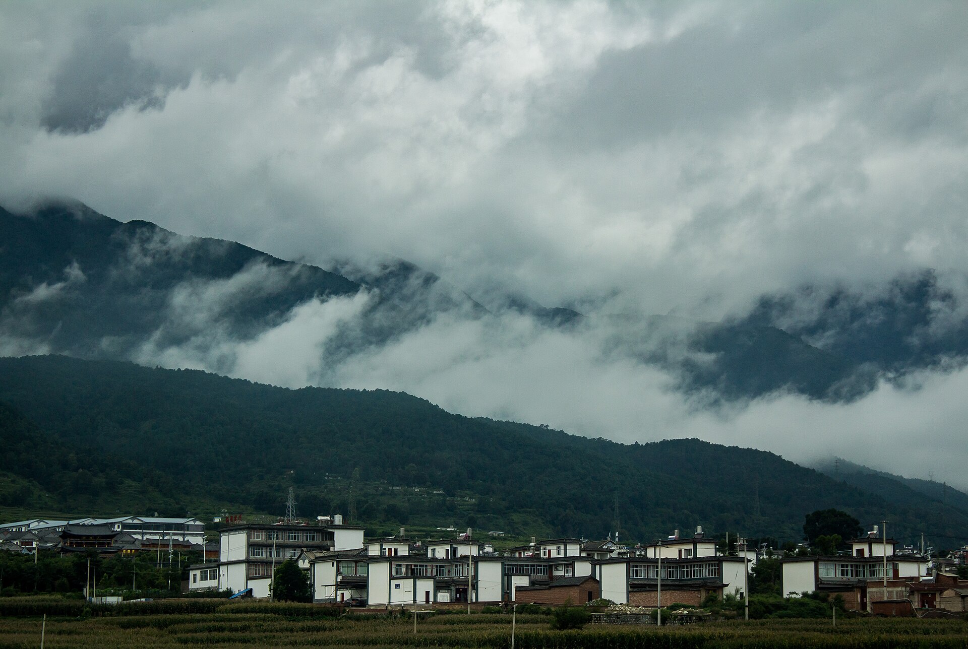 云南西北部山村：山地聚落与电力线路清晰可见。作者亲历的水、电、网络、卫生院和垃圾收运并非都能由照片验证。